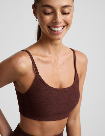 Woman wearing a brown sports bra and brown leggings against a plain background.