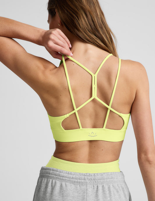 Woman wearing a lime sports bra and gray sweatpants against a plain background.
