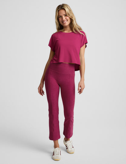 Woman wearing a magenta cropped short sleeve and magenta pintuck capri pants against a plain background.