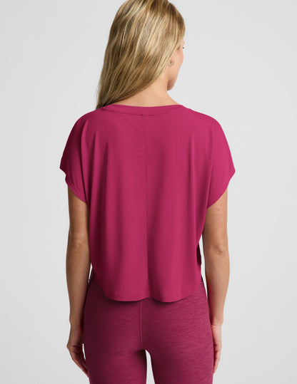Woman wearing a magenta cropped short sleeve and magenta pintuck capri pants against a plain background.