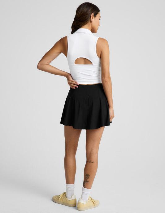Woman wearing the Black You're A force Skirt™ with a white sleeveless top and yellow sneakers, shown from a rear view.
