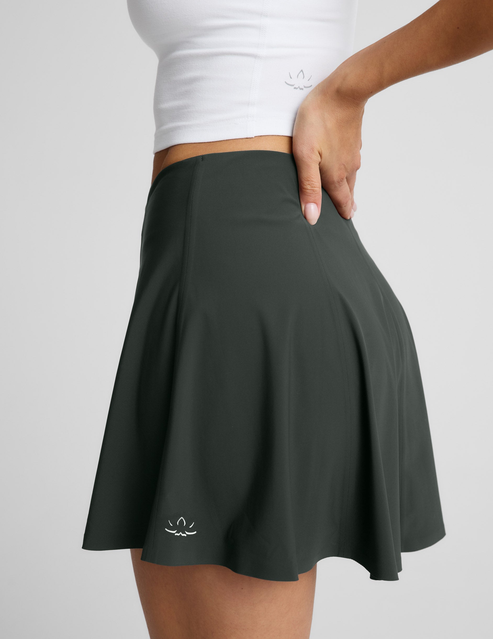 Side profile of woman wearing Green You're A force Skirt™ with a V-shaped waistline and a white tank top.
