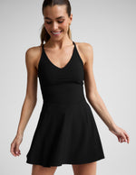 Woman wearing a black athletic dress against a plain background.