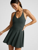 Woman wearing a dark green athletic dress with built-in shorts against a plain background.