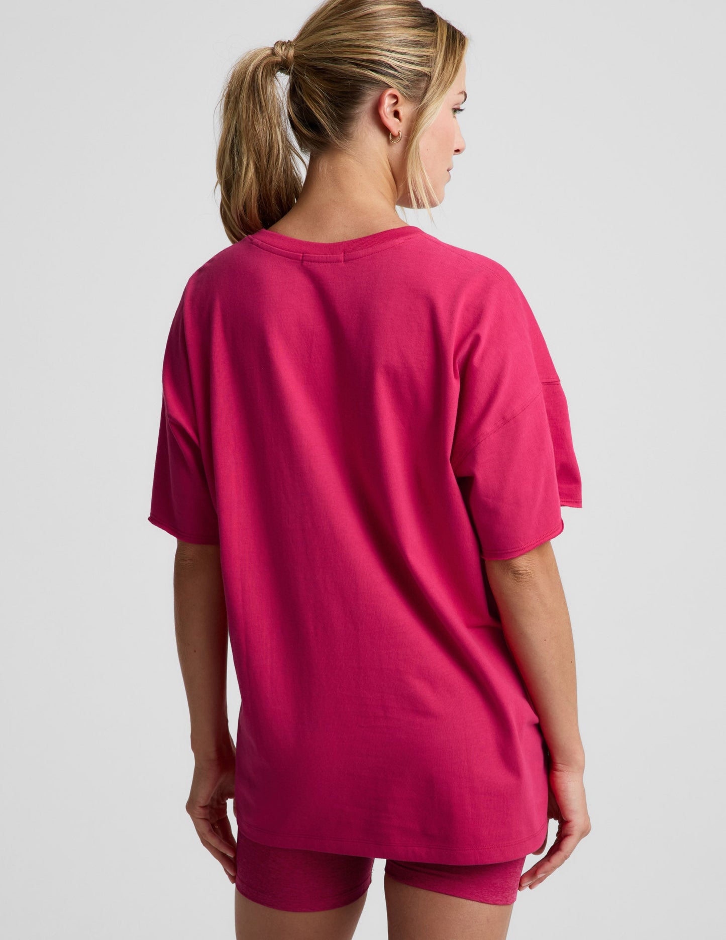 Woman wearing a red t-shirt and shorts against a plain background.