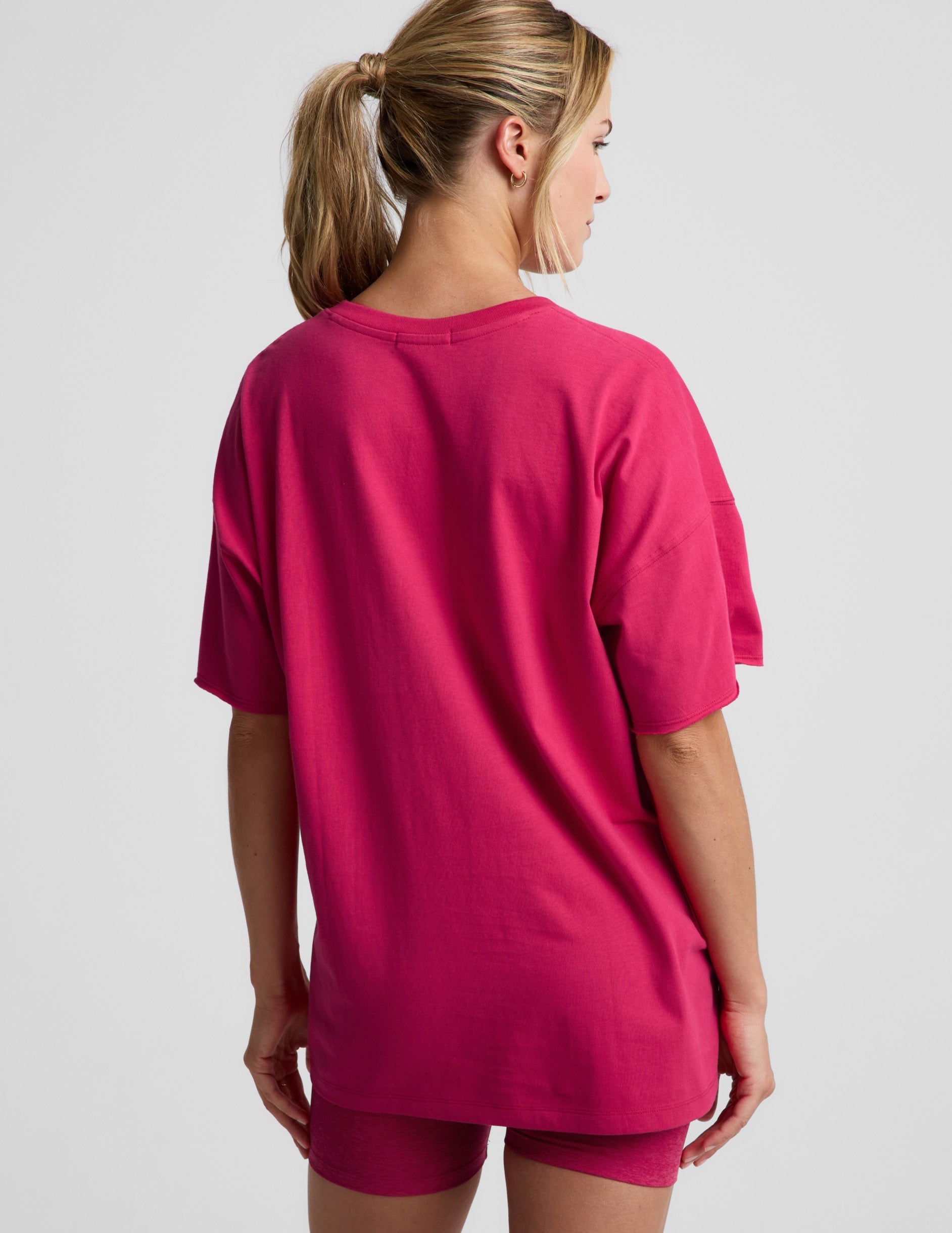 Woman wearing a red t-shirt and shorts against a plain background.