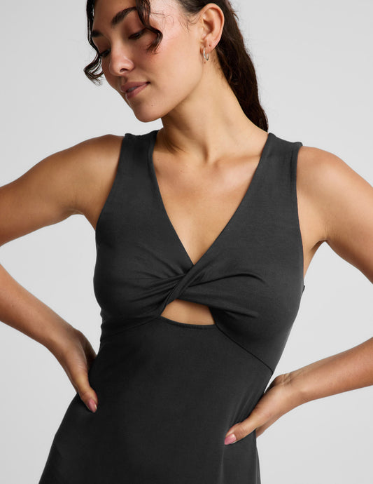 Woman wearing a black sleeveless midi dress with a cutout design on a light gray background.