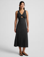 Woman wearing a black sleeveless midi dress with a cutout design on a light gray background.