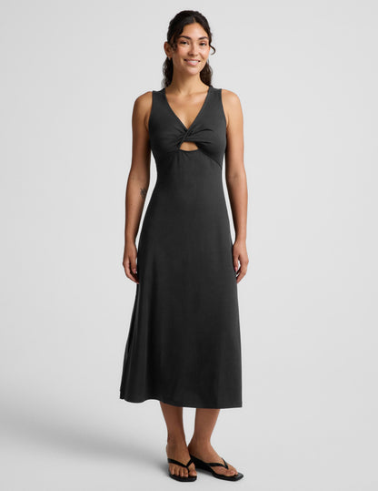 Woman wearing a black sleeveless midi dress with a cutout design on a light gray background.