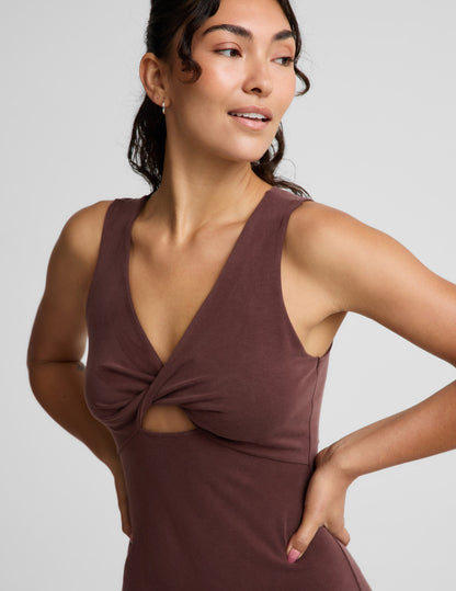 Woman wearing a brown sleeveless dress with a front center cutover on a light gray background.