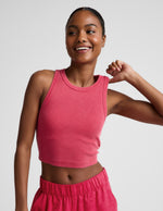 Woman wearing a red ribbed cropped tank top and red linen pants against a plain background.