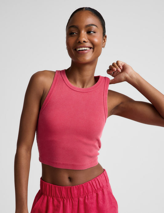 Woman wearing a red ribbed cropped tank top and red linen pants against a plain background.