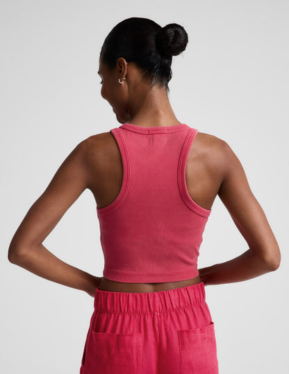 Woman wearing a red ribbed cropped tank top and red linen pants against a plain background.