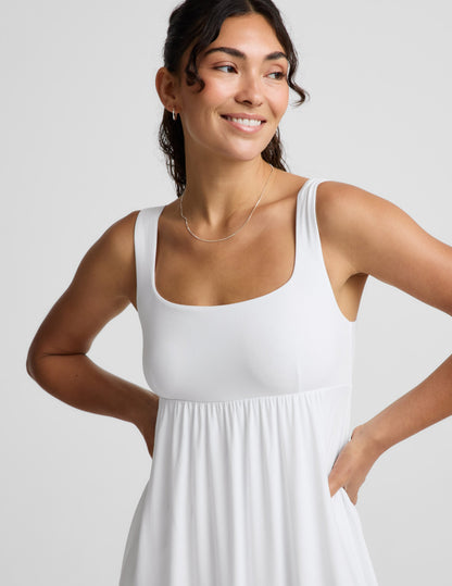 Woman wearing a white sleeveless dress on a plain background.