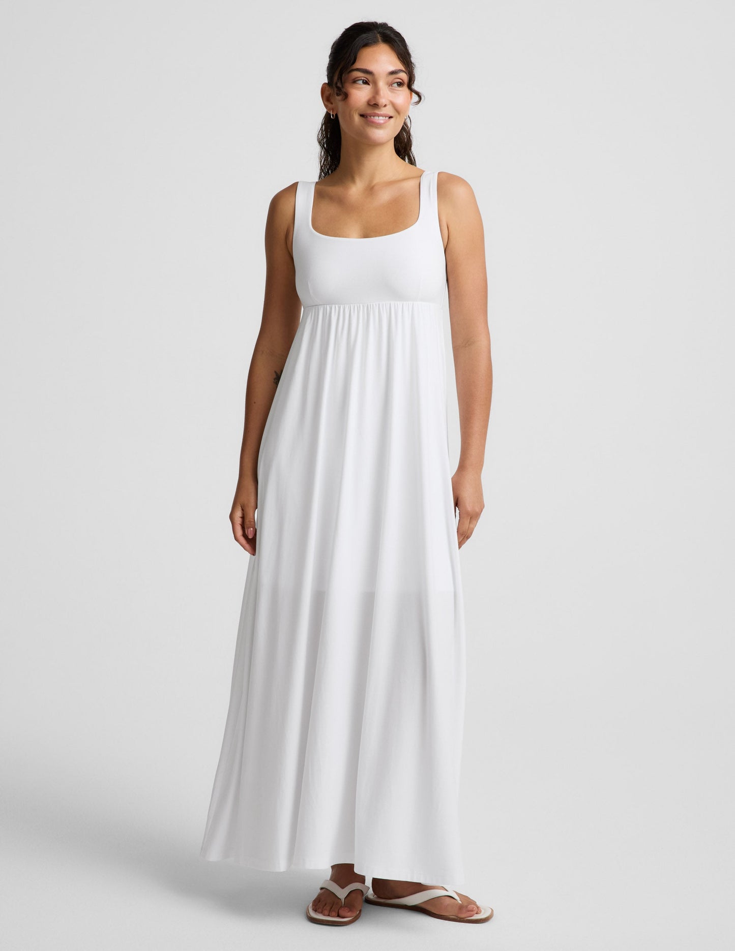 Woman wearing a white sleeveless dress on a plain background.