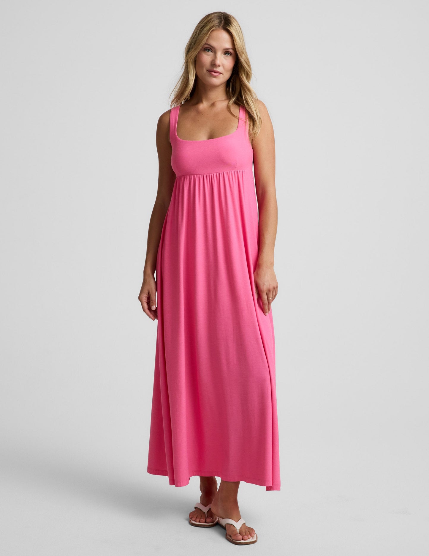 Woman wearing a pink maxi dress on a plain background.