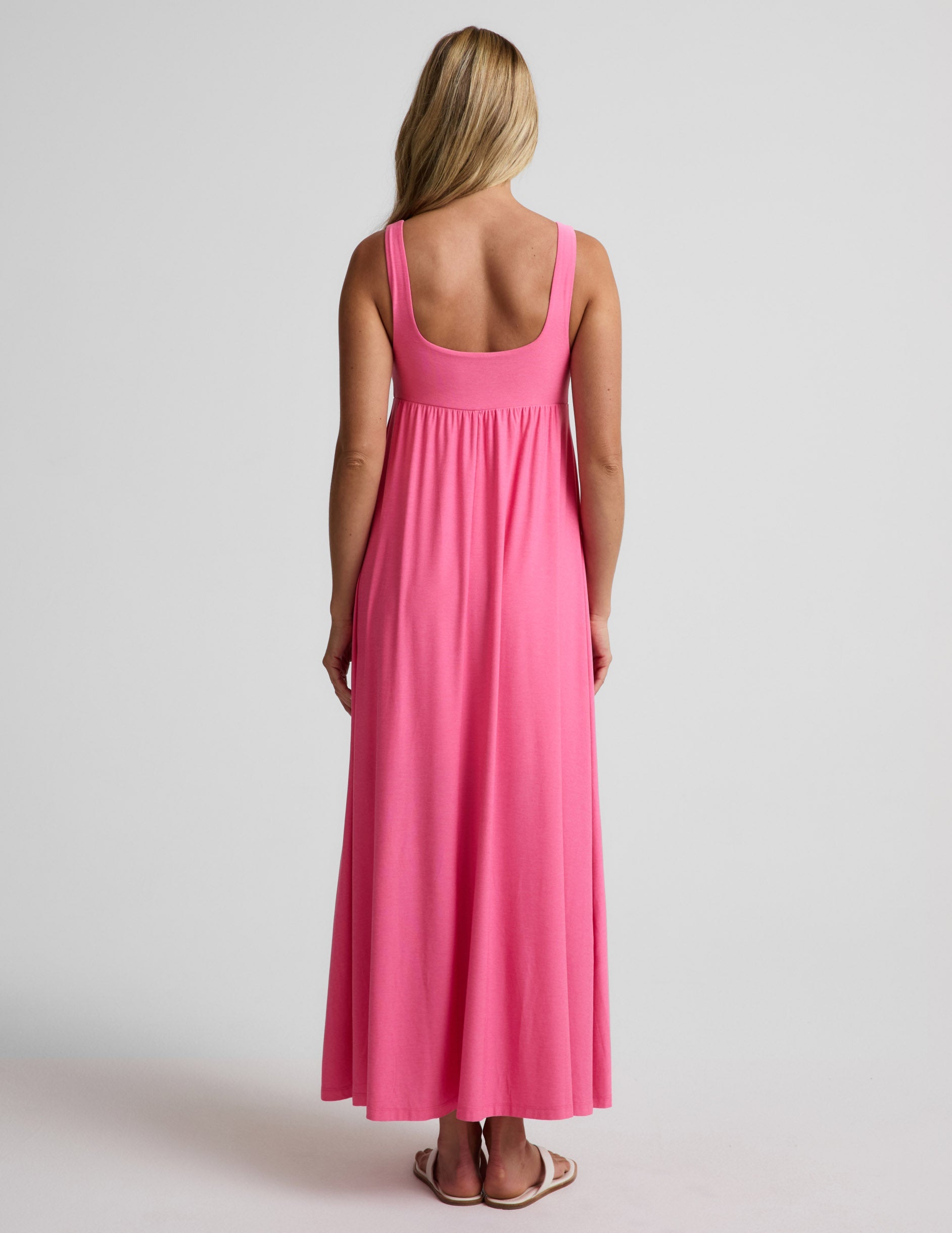 Woman wearing a pink maxi dress on a plain background.