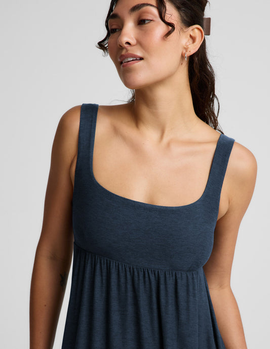 Woman wearing a navy blue sleeveless dress on a light gray background.