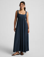 Woman wearing a navy blue sleeveless dress on a light gray background.