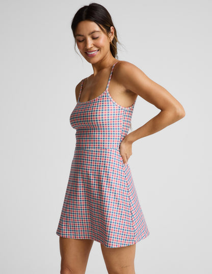 Woman wearing a gingham dress against a light gray background.