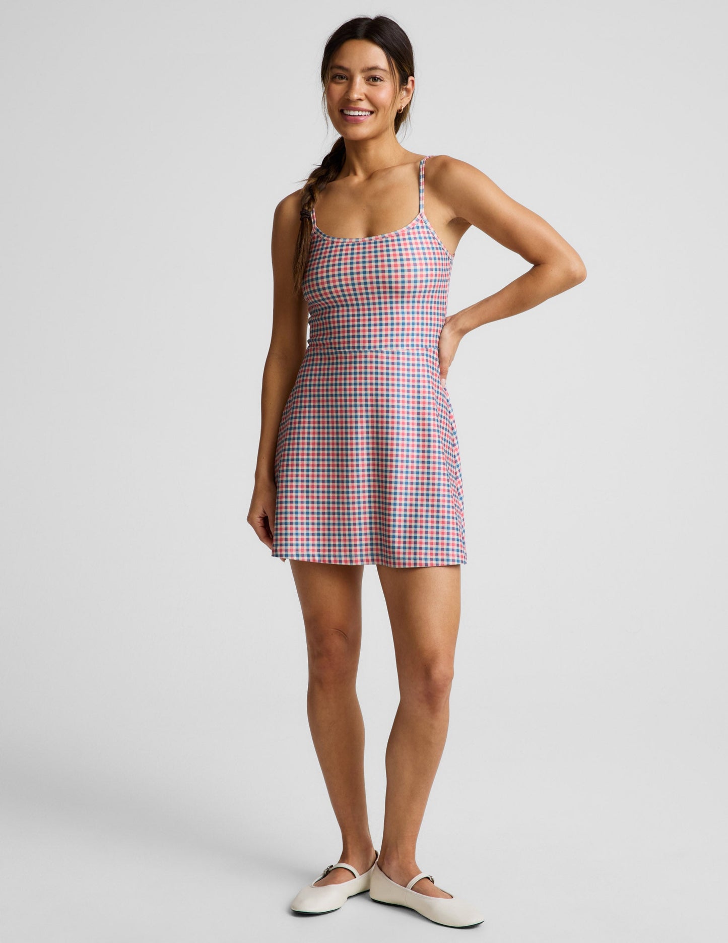 Woman wearing a gingham dress against a light gray background.