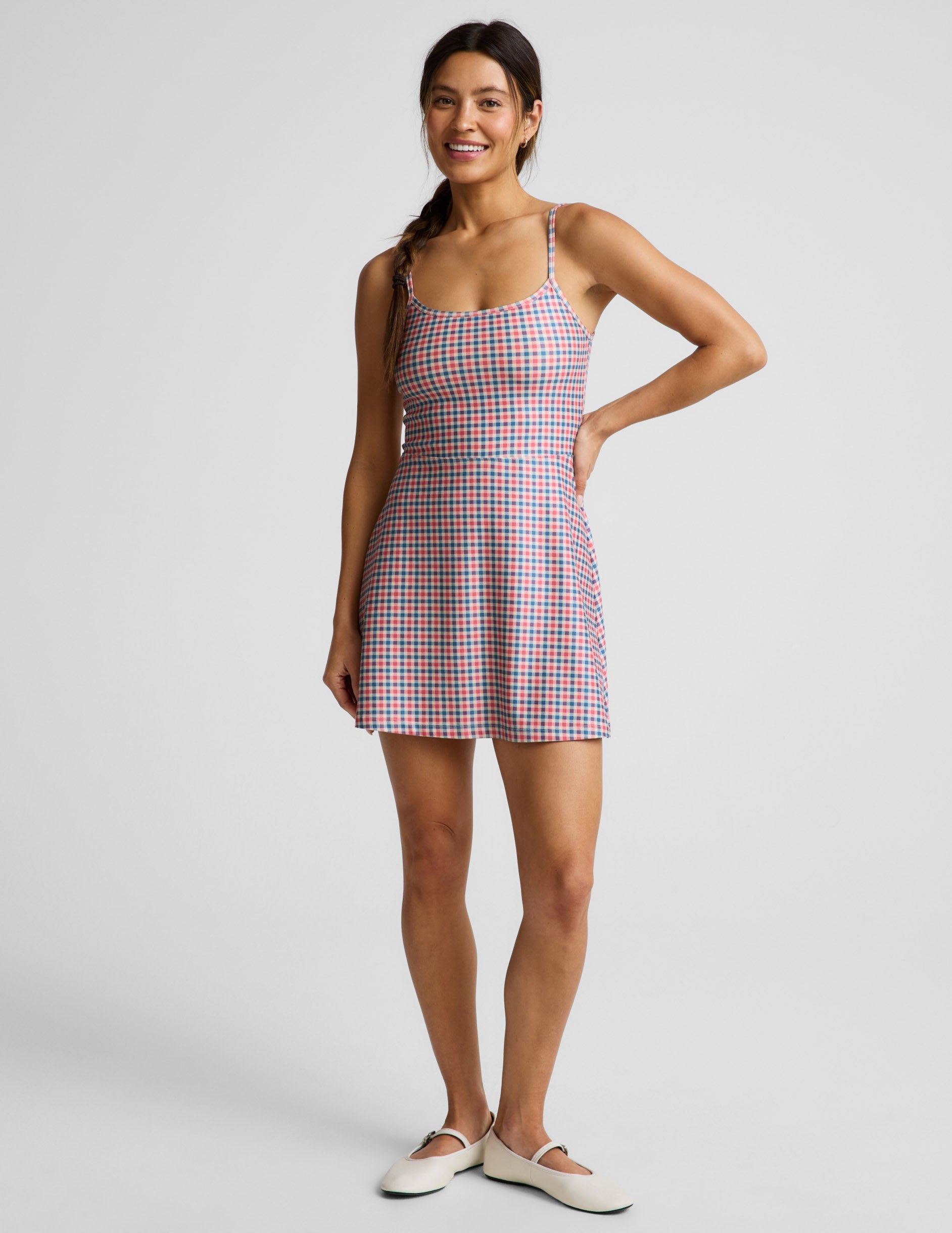 Woman wearing a gingham dress against a light gray background.
