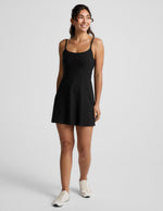Woman wearing a black mini tank dress against a light gray background.