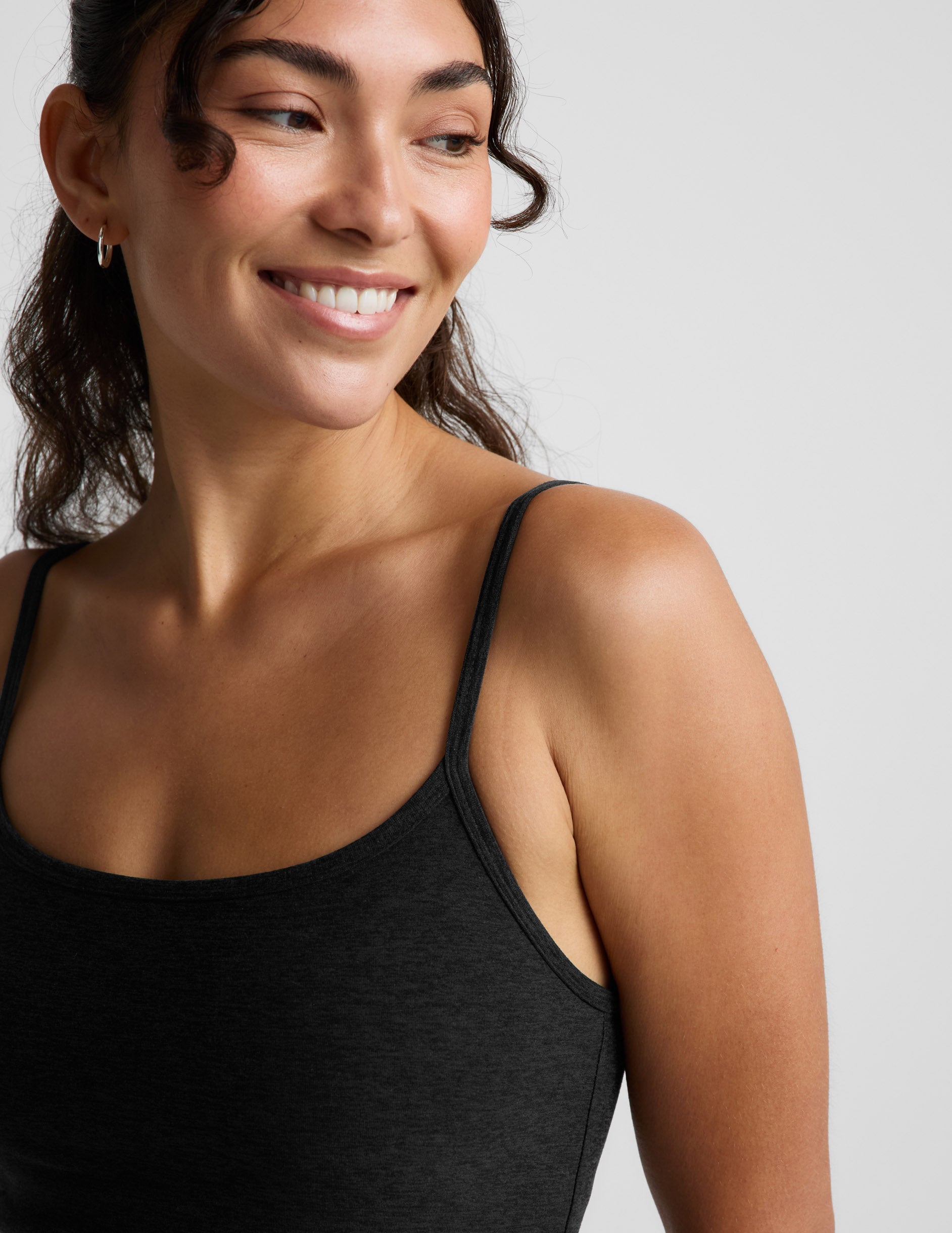 Woman wearing a black mini tank dress against a light gray background.