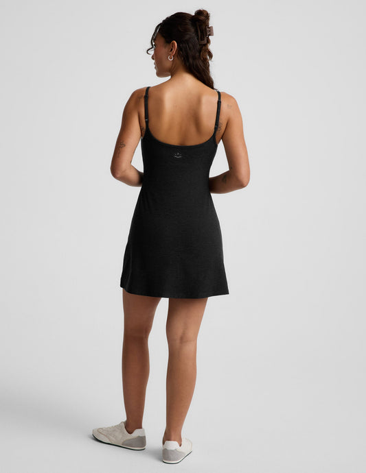 Woman wearing a black mini tank dress against a light gray background.