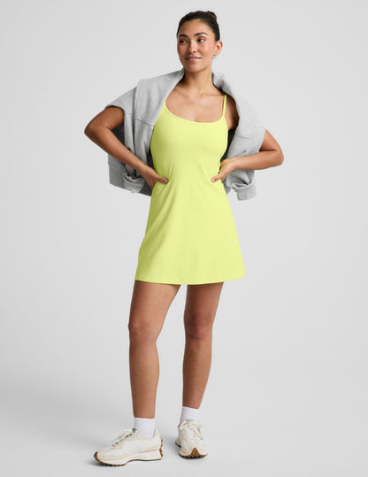 Woman wearing a yellow mini dress against a light gray background.