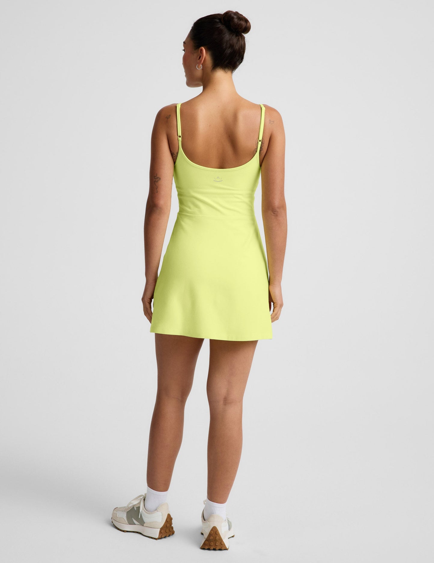 Woman wearing a yellow mini dress against a light gray background.