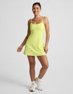 Woman wearing a yellow mini dress against a light gray background.