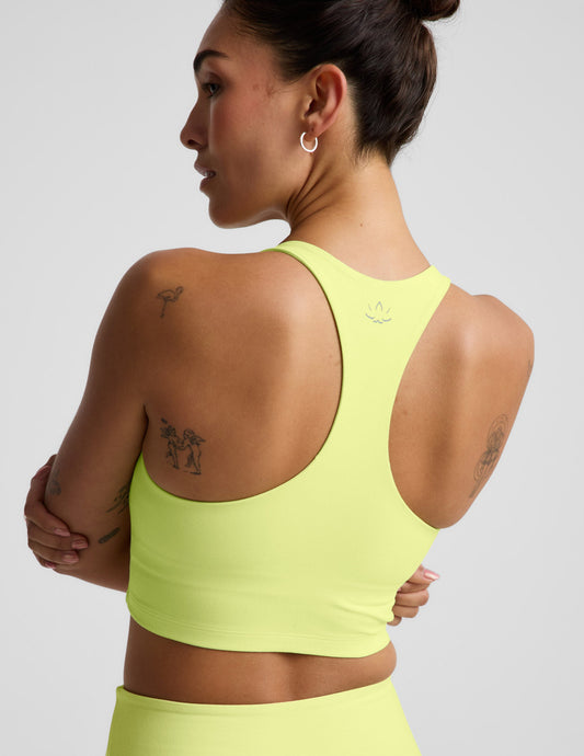 Woman wearing a bright yellow cropped tank and biker shorts against a plain background.