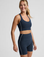 Woman wearing a navy blue cropped tank and biker shorts against a plain background.
