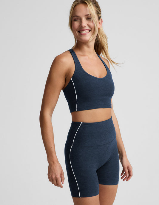 Woman wearing a navy blue cropped tank and biker shorts against a plain background.