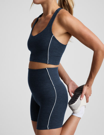 Woman wearing a navy blue cropped tank and biker shorts against a plain background.
