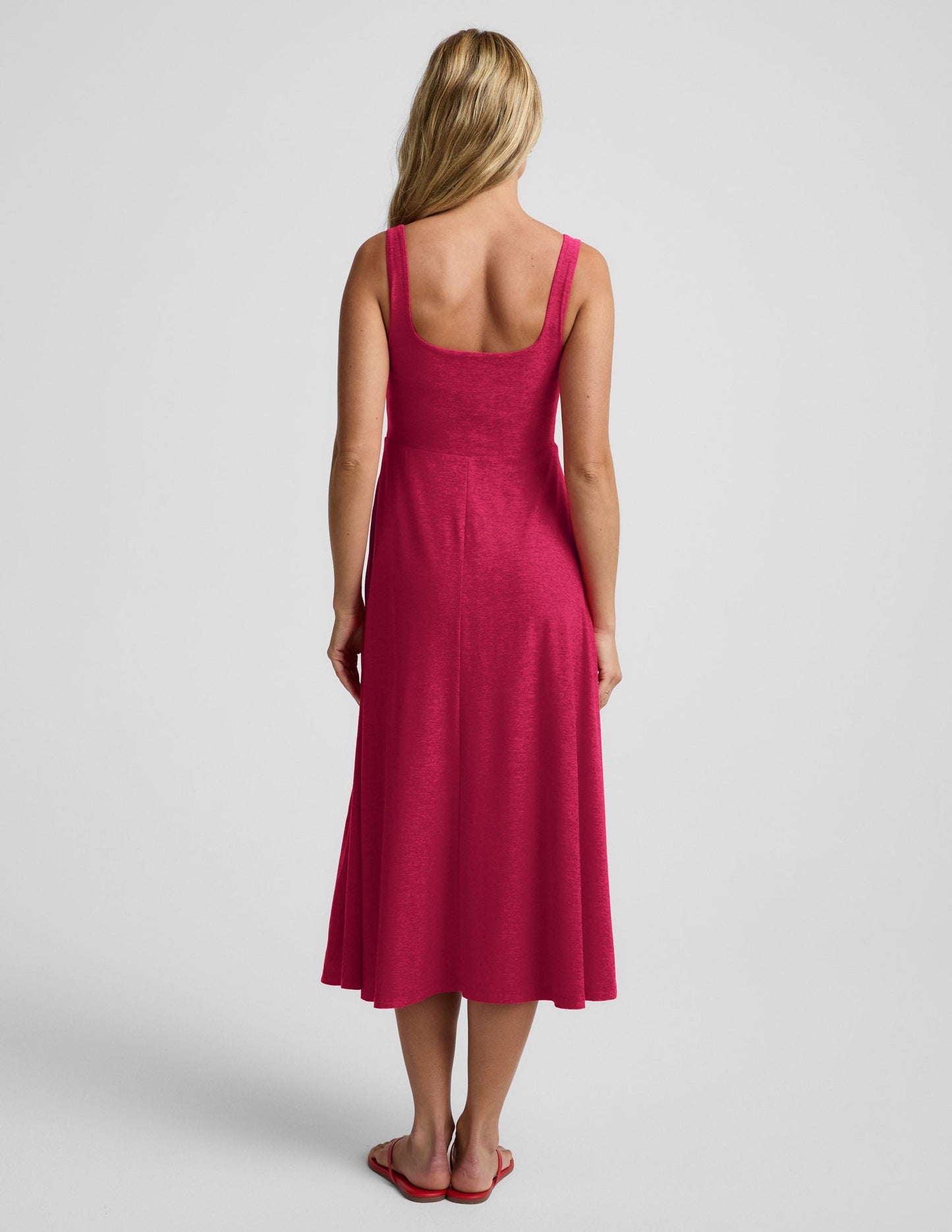 Woman wearing a red square neck tank midi dress on a plain background.