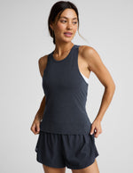 Woman wearing a blue active racerback tank and blue run shorts against a plain background.