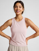 Woman wearing a pink sleeveless active tank and beige shorts against a plain background.