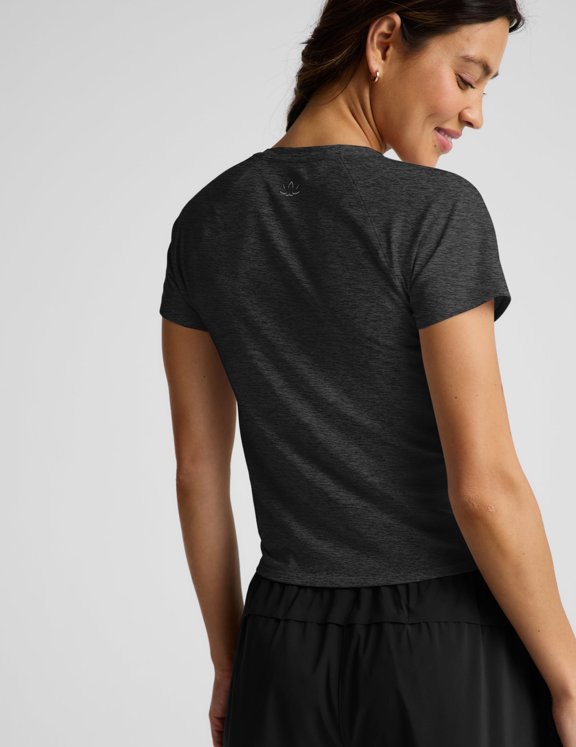 Woman wearing a dark gray t-shirt and black shorts on a light gray background.