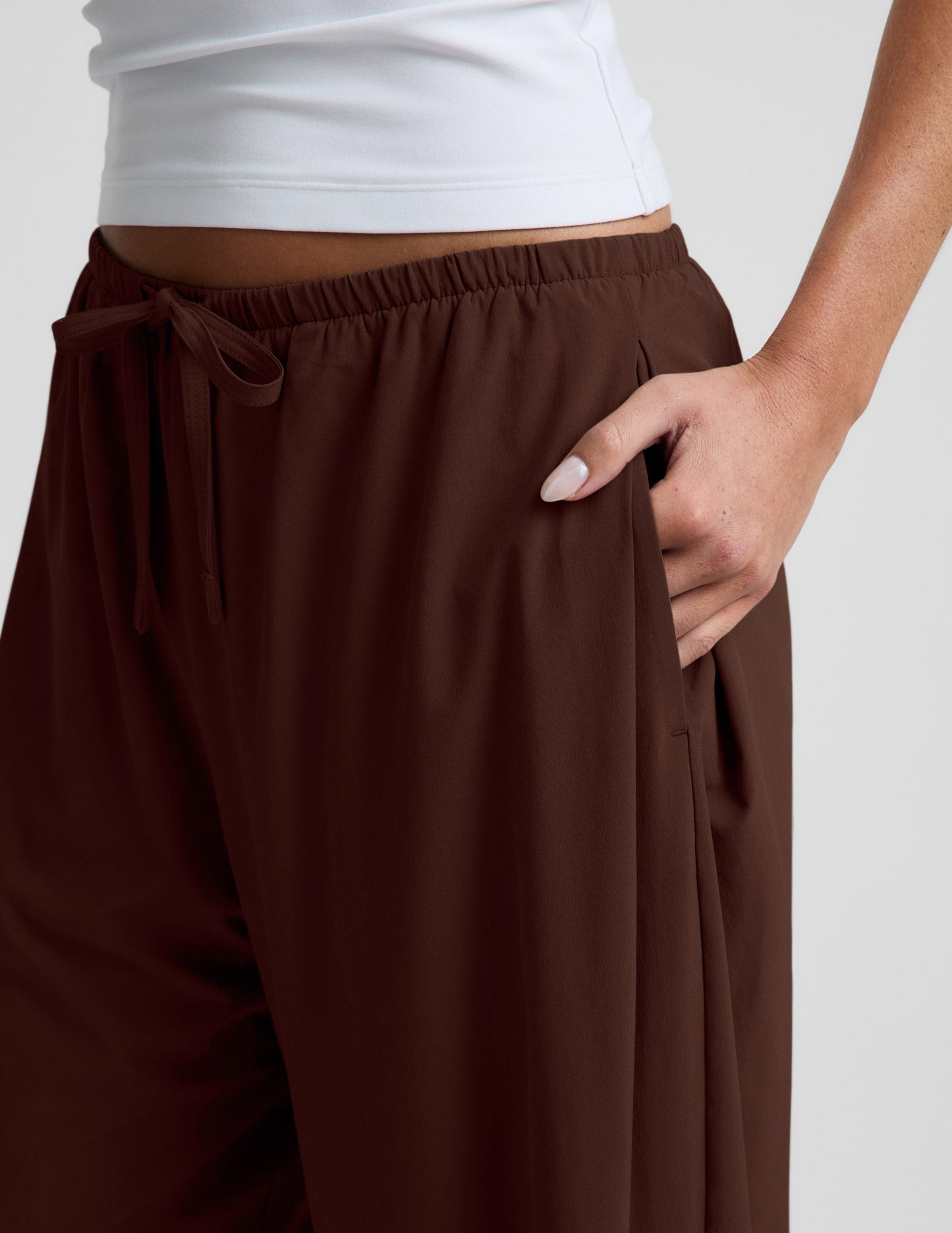 Close-up of woman wearing Brown Solstice™ Drawstring Wide Leg Pant 29" with hand in side pocket and white top.