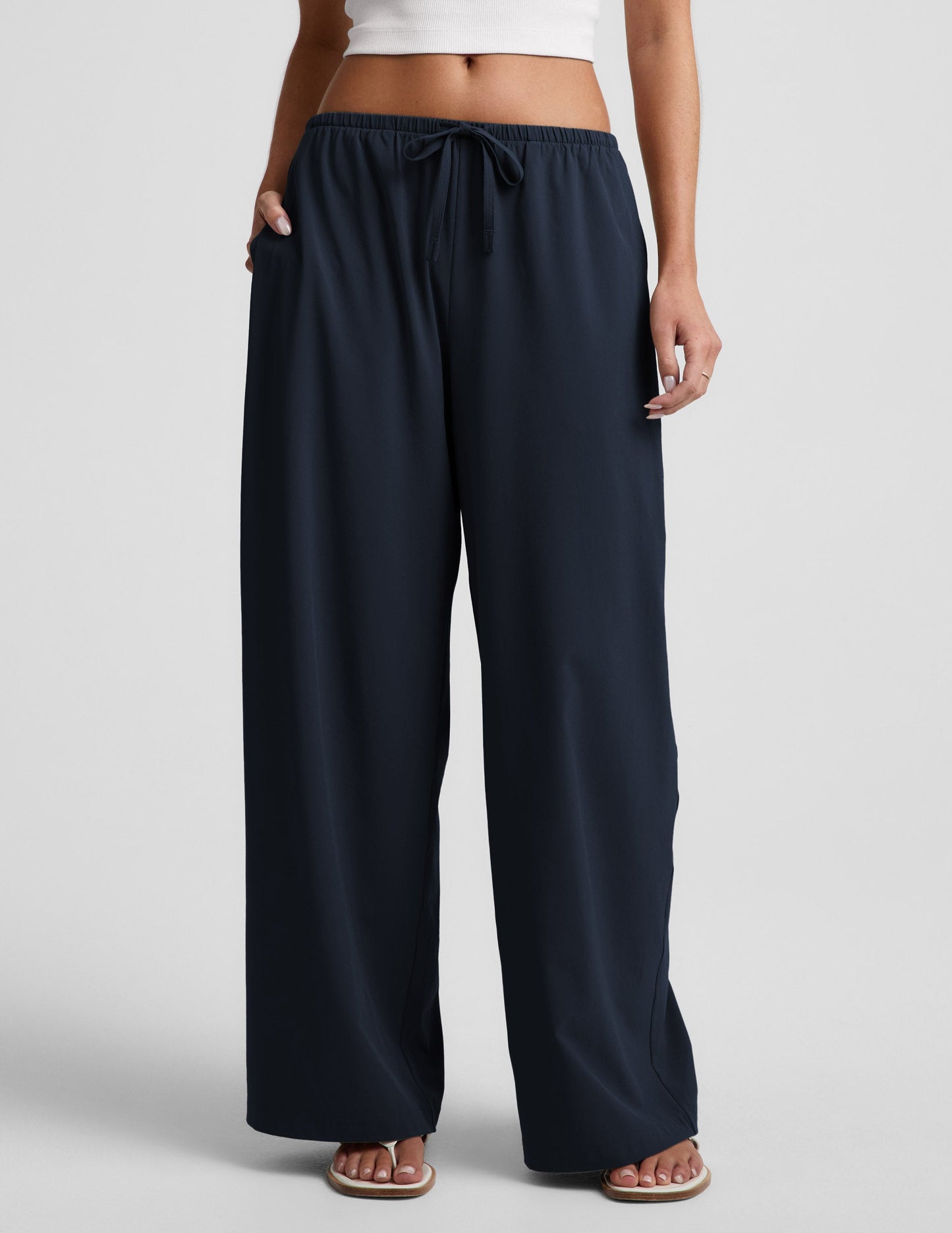 Woman wearing Navy Solstice™ Drawstring Wide Leg Pant 29" with side pockets, paired with a white crop top and sandals.