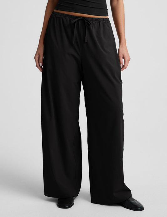 Woman wearing black Solstice Drawstring Wide Leg Pant 31" with a black tank top and black loafers.
