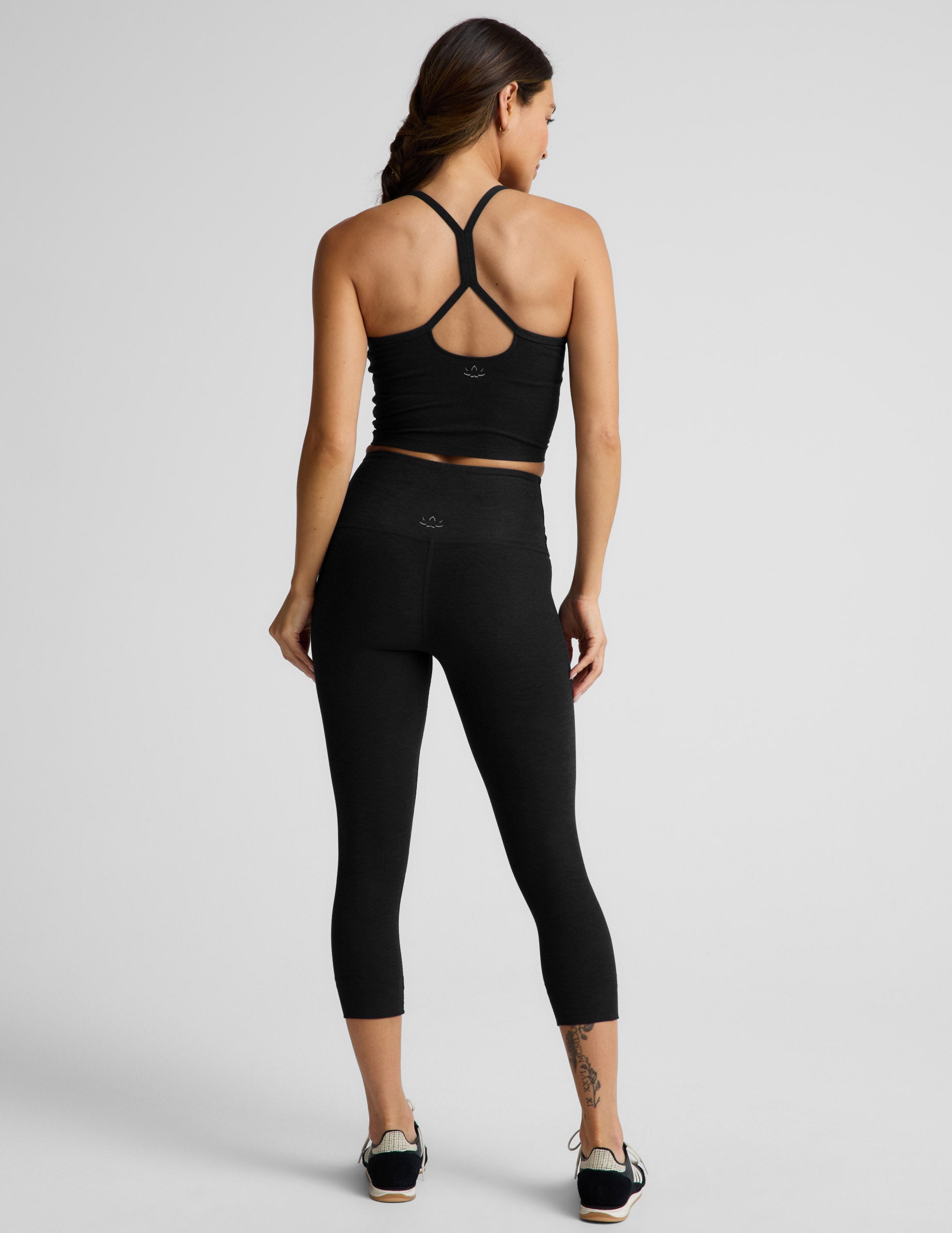 Woman wearing Black Spacedye™ Walk And Talk High Waisted Capri Legging with a matching tank top, rear view.