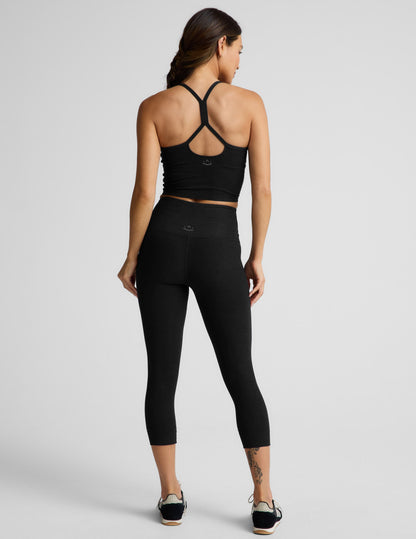 Woman wearing Black Spacedye™ Walk And Talk High Waisted Capri Legging with a matching tank top, rear view.