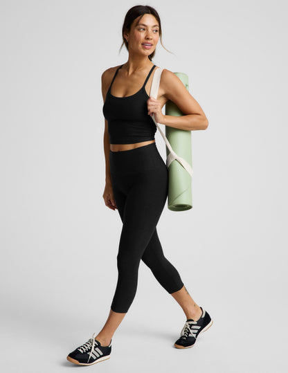 Woman wearing Black Spacedye Walk And Talk High Waisted Capri Legging™ paired with a black crop top and green yoga mat.