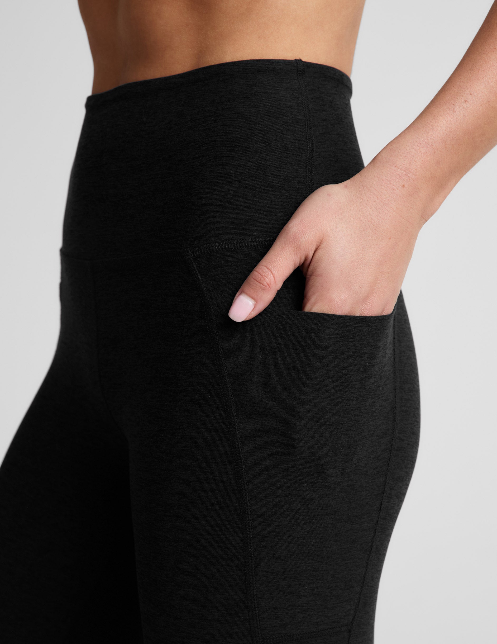 Woman wearing Black Spacedye™ Out Of Pocket High Waisted 20.5" Capri Legging with her hand tucked into a side slant pocket.