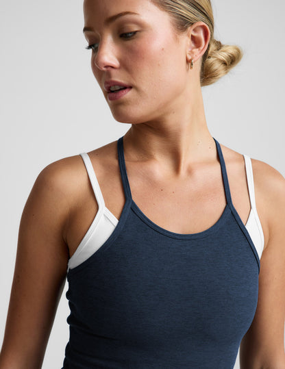 Woman wearing a navy and white layered tank and shorts against a plain background.