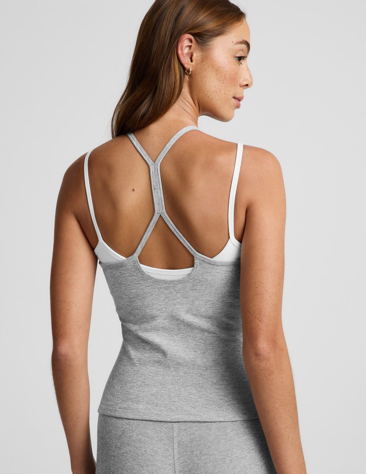 Woman wearing a gray tank top and shorts set on a light gray background.