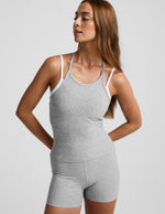 Woman wearing a gray tank top and shorts set on a light gray background.